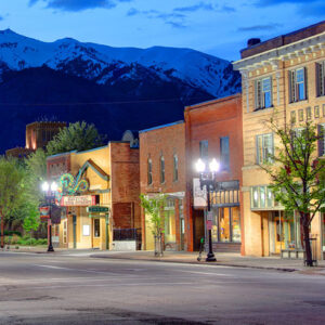A quiet street scene at dusk, showcasing charming brick buildings with mountain views in the background.